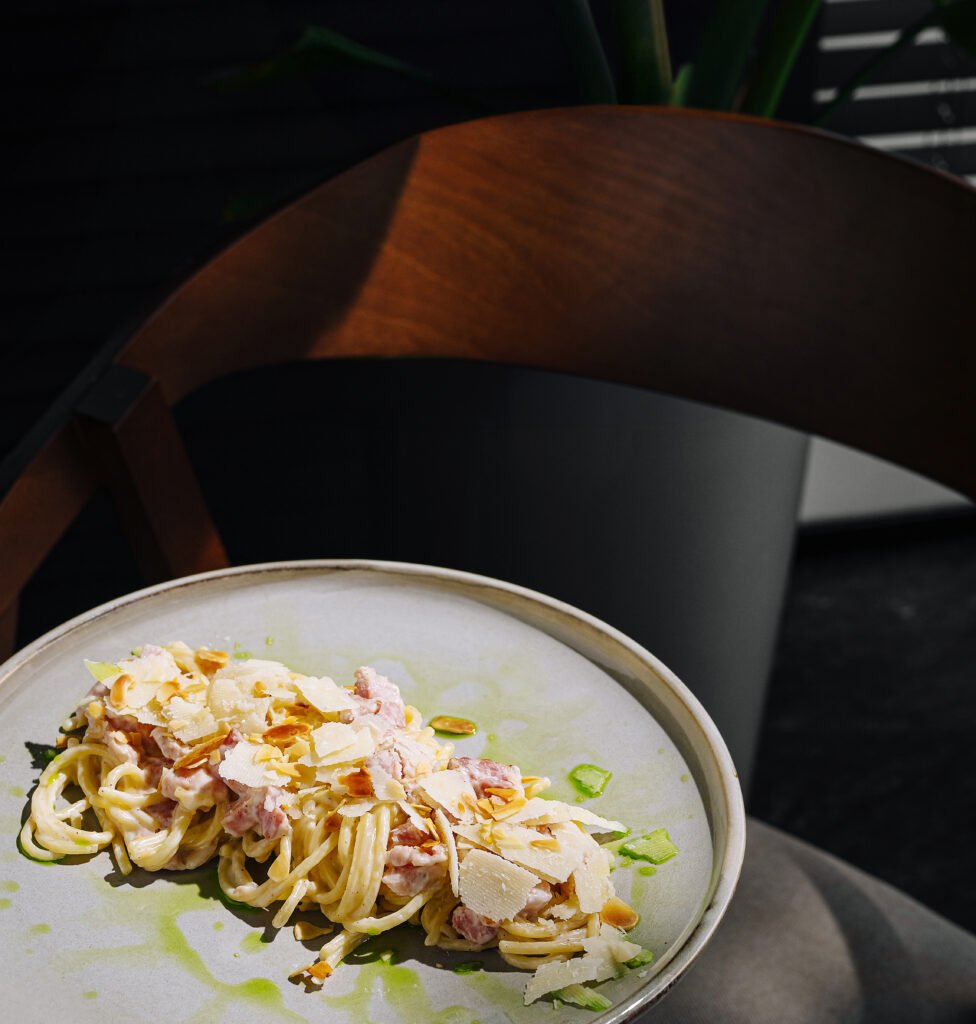 Plato de pasta servido en un plato en un entorno moderno durante el día.